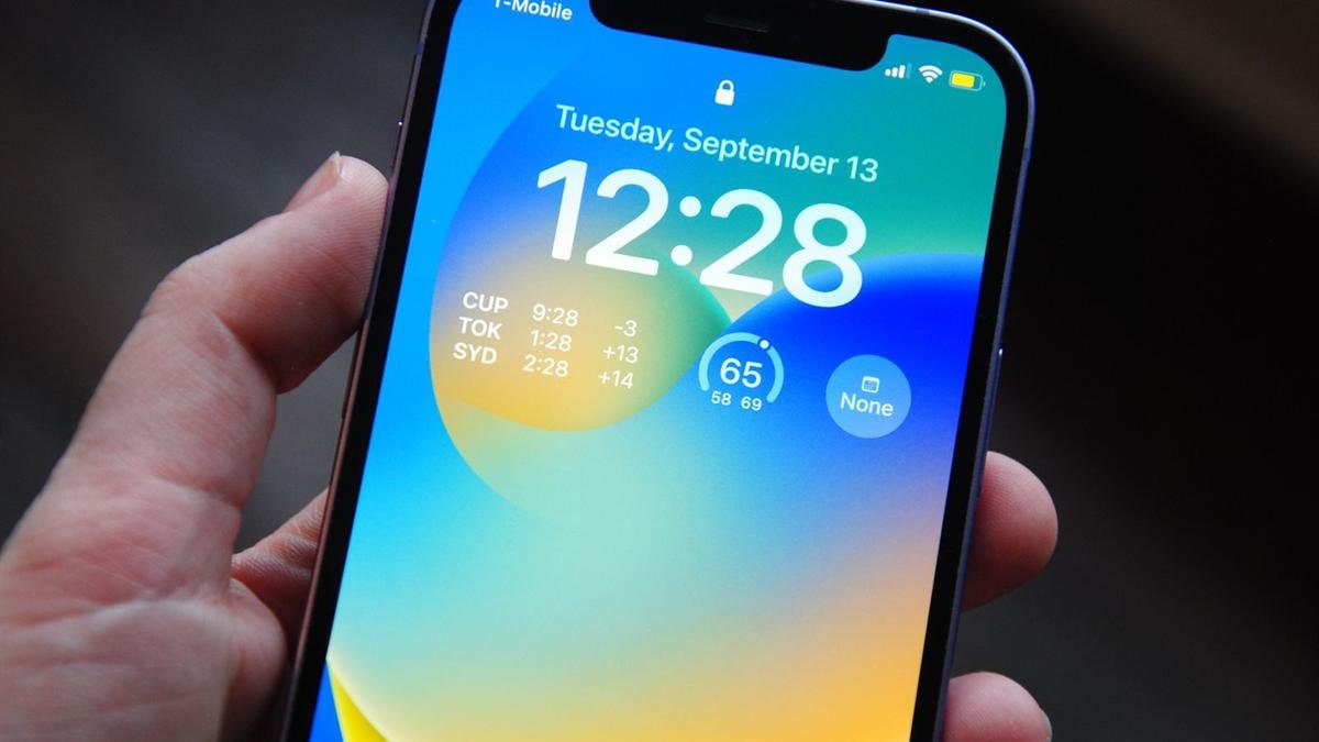 A hand holding an iPhone showing its lock screen with the date and time