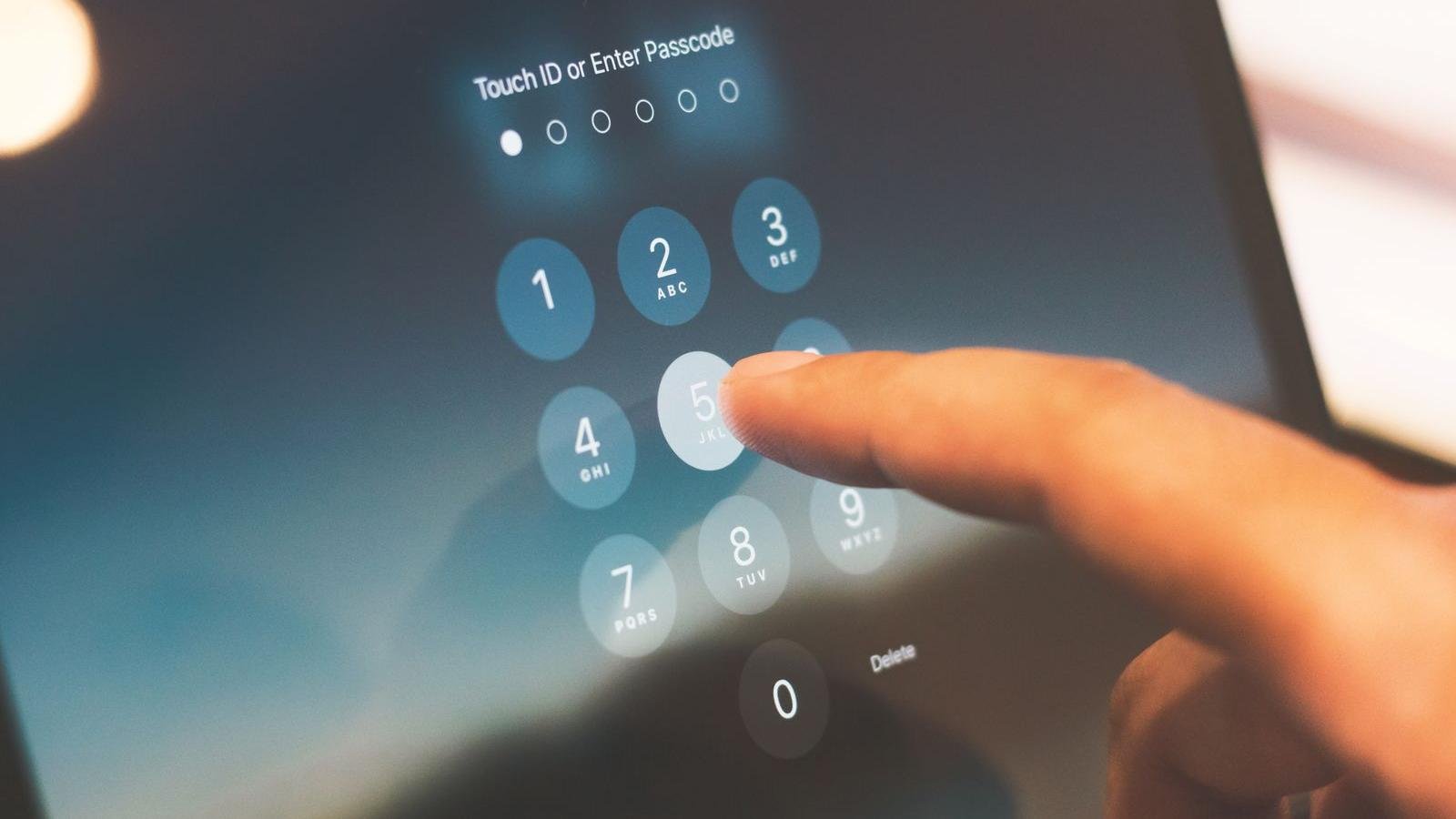 Finger entering a passcode on a lock screen