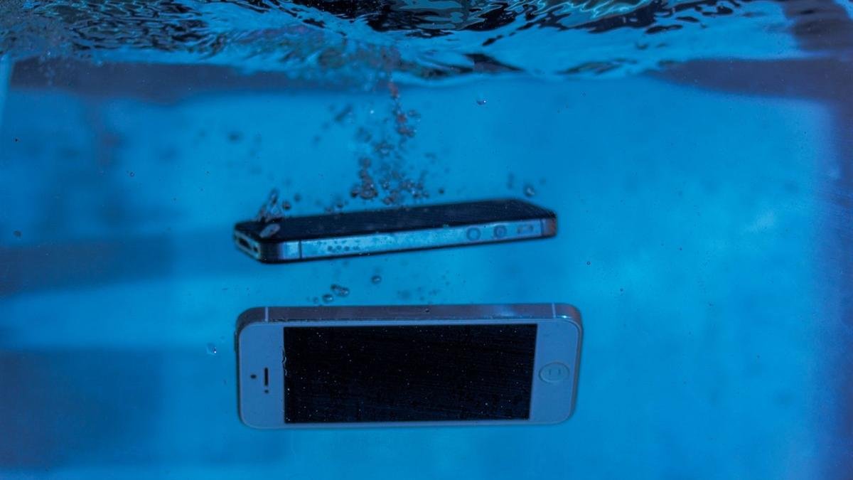 Two smartphones sinking in clear blue water with air bubbles rising